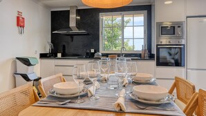 A modern kitchen with white cabinets, a black countertop, and a large window. - Vale dos Amores, a Home in Madeira (Calheta)