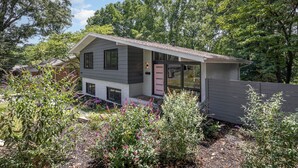 A modern two-story house with a grey exterior, a pink door, and a small porch area. - Charming 3-bedroom house with spacious backyard in enjoyable Charlotte.  (Charlotte)