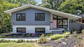 A modern two-story house with a grey exterior, large windows, and a well-maintained garden. - Charming 3-bedroom house with spacious backyard in enjoyable Charlotte.  (Charlotte)