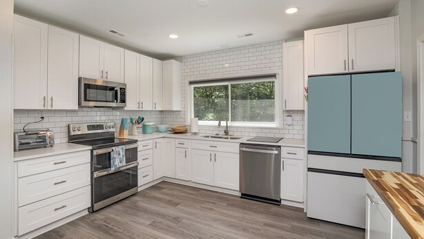A modern kitchen with white cabinets, stainless steel appliances, and a window providing natural light. - Charming 3-bedroom house with spacious backyard in enjoyable Charlotte.  (Charlotte)