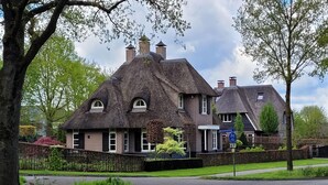 A traditional house with a thatched roof, brick walls, and a small garden.