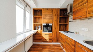 Eine moderne Küche mit Holzschränken, einem eingebauten Backofen und einem großen Fenster.