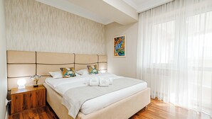 Ein Schlafzimmer mit einem großen Bett, einem Nachttisch mit Lampe, Holzboden und einem Bild an der Wand.