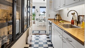 Een moderne keuken met witte kastjes, een houten aanrecht en een zwart-wit schaakbordvloer.