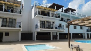 A multi-story residential building with balconies, a swimming pool, and a covered outdoor seating area. - Paramount Gardens Resorts C202 (Tersefanou)