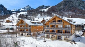 A chalet-style hotel with multiple balconies, wooden architecture, and a mountainous backdrop.