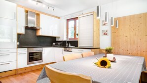 Een moderne keuken met witte kasten, een inbouwoven en een eethoek met een tafel gedekt voor twee personen.