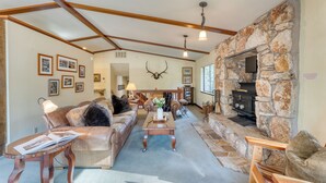 A cozy living room with a stone fireplace, wooden beams, and a comfortable seating area. - Wildwood by AvantStay | Hot Tub, 5mins to Lake (Tahoe Vista)