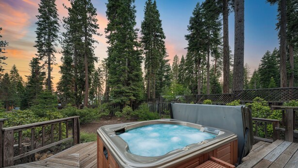 A hot tub on a wooden deck surrounded by tall trees and a wooden fence. - Wildwood by AvantStay | Hot Tub, 5mins to Lake (Tahoe Vista)