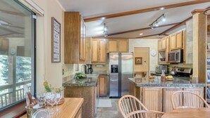 A modern kitchen with wooden cabinets, stainless steel appliances, and a large island with seating. - Wildwood by AvantStay | Hot Tub, 5mins to Lake (Tahoe Vista)