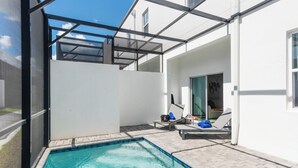 En swimmingpool med liggestole og en overdækket terrasse.