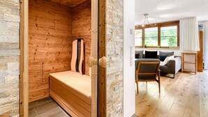 Une salle de sauna avec des murs en bois et un banc, un espace de vie avec un canapé et une table, et une fenêtre avec des rideaux.