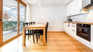 Une cuisine moderne avec une table et des chaises en bois, des armoires blanches et une grande fenêtre donnant sur un paysage enneigé.