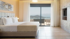 Quarto com uma cama grande, televisão e vista para o mar.
