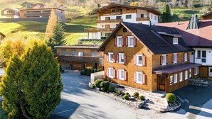 A multi-story hotel with a traditional Alpine architectural style, featuring a prominent entrance and a parking area. - Appartement Zentral de Luxe (Brand)