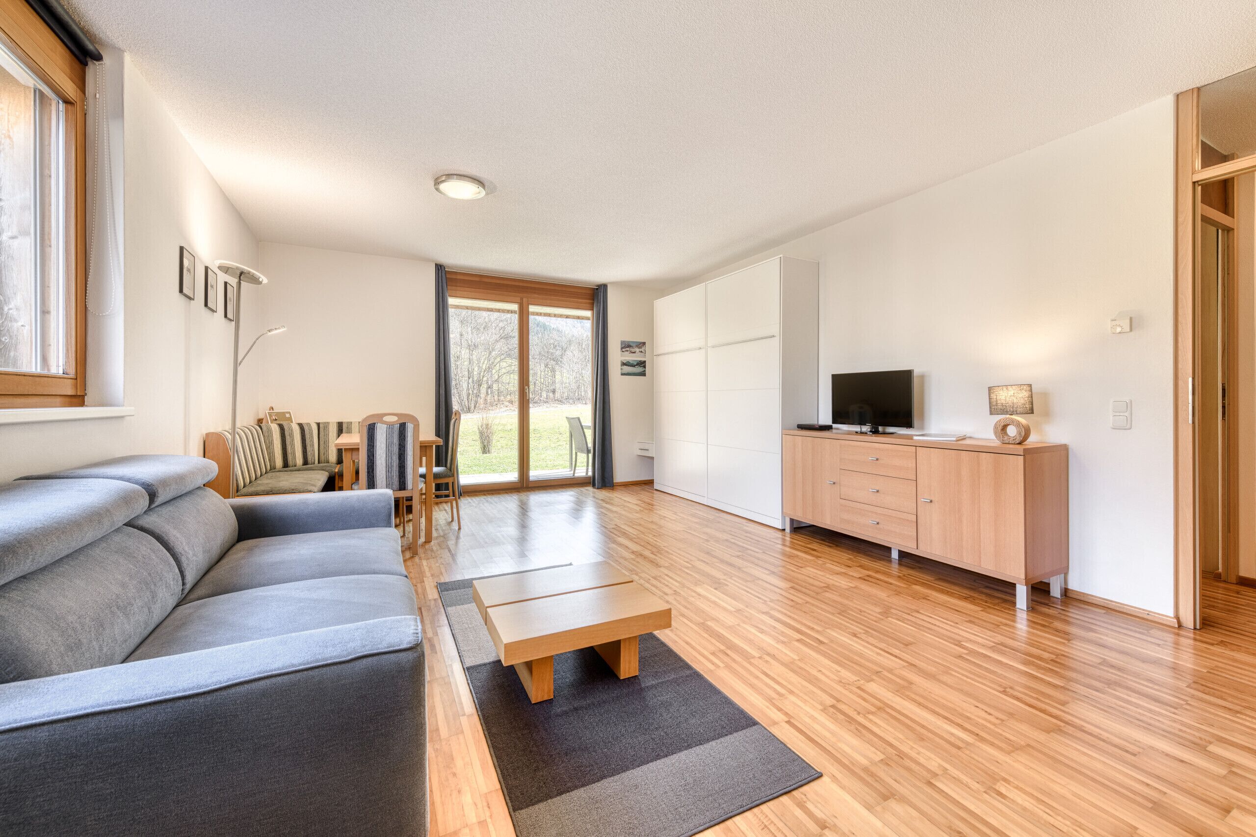 A modern living room with a sofa, a coffee table, a TV, and a wooden cabinet.