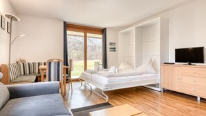 A modern room with a bed, sofa, TV, and a desk. - Garden appartment Kirchdorf (Brand)