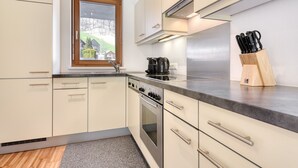 A modern kitchen with a window, stainless steel appliances, and a knife block. - Garden appartment Kirchdorf (Brand)