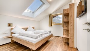 Un dormitorio moderno con tragaluz, estructura de cama de madera y estanterías empotradas de madera.