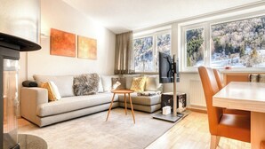 A modern living room with a sofa, a coffee table, a TV, and a dining area with a table and chairs.