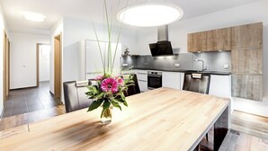 Une cuisine moderne avec une table à manger en bois, un vase de fleurs et un luminaire suspendu.