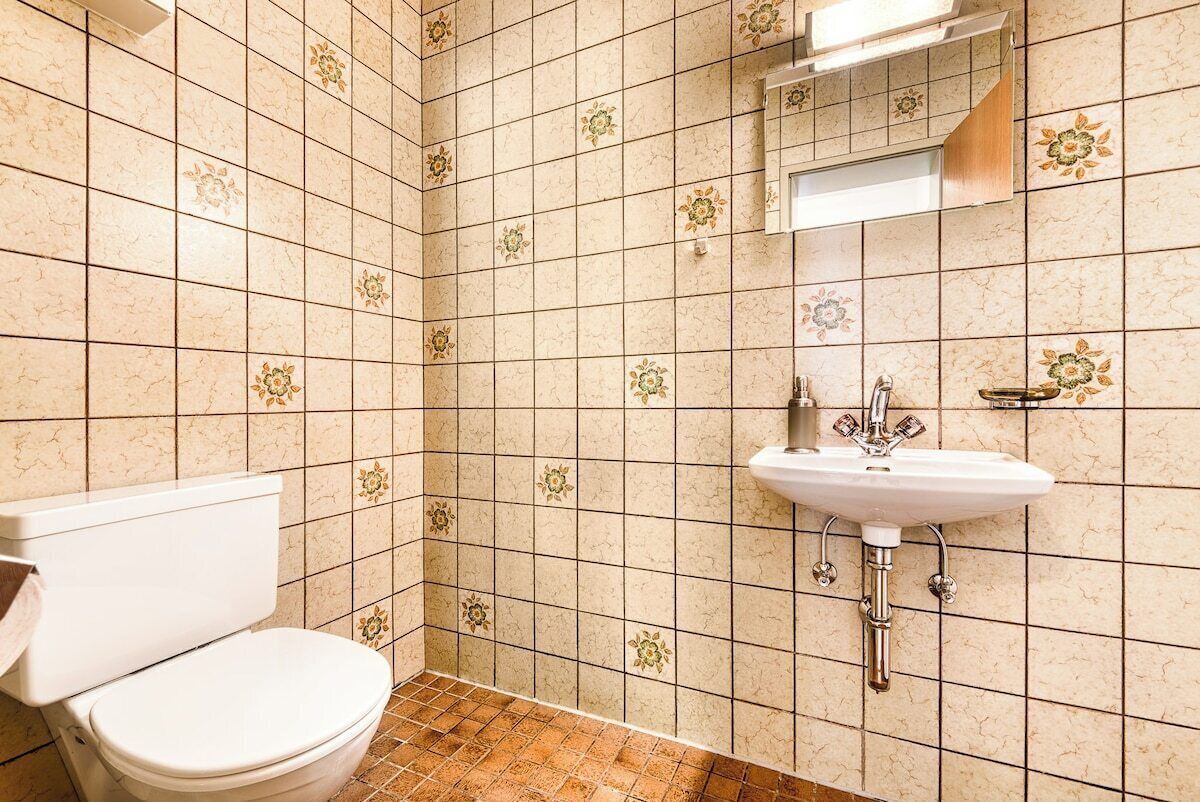 Ein Badezimmer mit Toilette, Waschbecken und gefliesten Wänden.