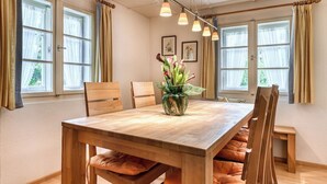 A dining area with a wooden table, cushioned benches, and a potted plant. - Chalet Mariedl (Tschagguns)