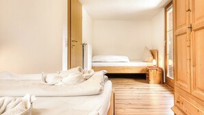 A bedroom with a wooden floor, a bed with white linens, a nightstand with a lamp, and a wardrobe. - Chalet Mariedl (Tschagguns)