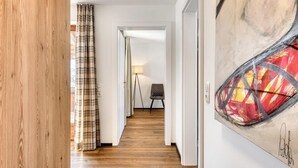 Ein Flur mit Holzboden, einem Karomuster-Vorhang, einer Lampe und einem Sessel.
