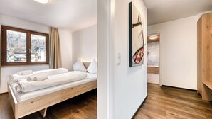 Ein Zimmer mit einem hölzernen Bett, einem großen Fenster und einem Gemälde an der Wand.