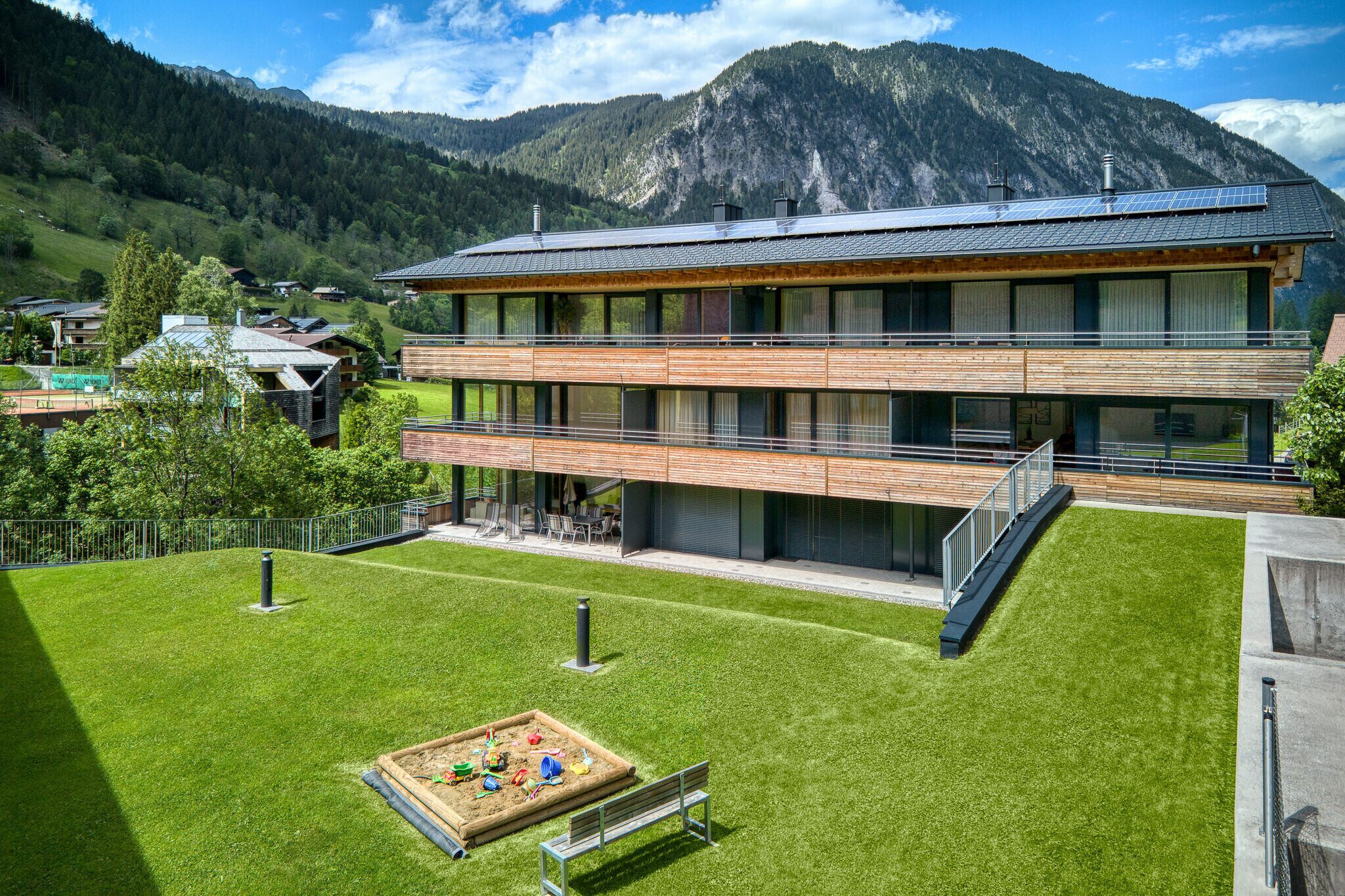 Un edificio moderno con techo plano, ventanas amplias y fachada de madera.