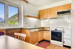 Eine Küche mit Holzausstattung, einem Geschirrspüler, einem Backofen und einem Fenster mit Blick auf die Berge.