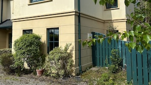A two-story building with a beige facade, a green roof, and a blue fence. - 7 Oakwood Manor Kenmare (Kenmare)