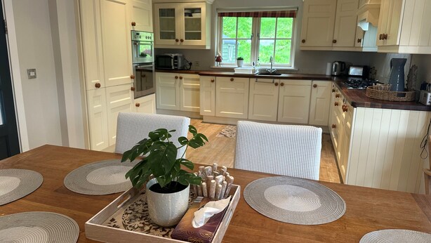 A spacious kitchen with white cabinetry, a dining table with placemats, and a potted plant. - 7 Oakwood Manor Kenmare (Kenmare)