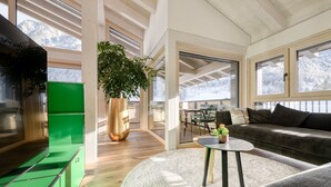 Una sala moderna con un sofá verde, una mesa de centro redonda y una planta grande en maceta.