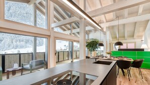 Una cocina moderna con una isla grande, suelo de madera y amplios ventanales con vistas a un paisaje nevado.