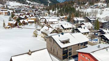 Un pueblo cubierto de nieve con casas de madera tradicionales y edificios modernos, rodeado de montañas.
