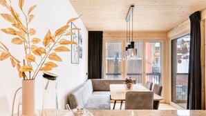 Un interior moderno con zona de comedor, sofá y un amplio ventanal con vistas a edificios.