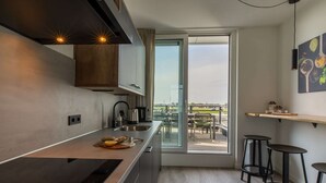 Cozinha moderna com uma ilha grande, forno embutido e vista para um pátio externo através de uma porta de vidro.