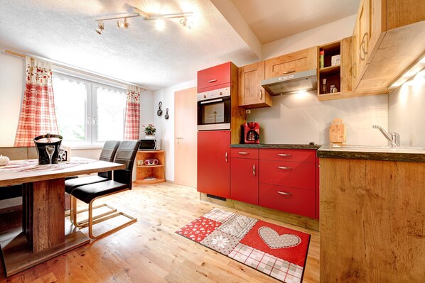 Una cucina moderna con mobili rossi, un tavolo da pranzo in legno e un tappeto con motivi rossi e bianchi.