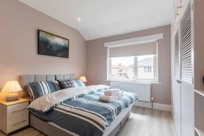 Une chambre à coucher avec un lit, des tables de chevet, une fenêtre et un radiateur.
