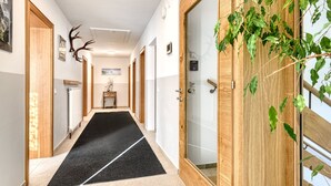 A hotel hallway with a black carpet, wooden doors, and a deer antler decoration. - Holiday apartment Aurora (St. Gallenkirch)