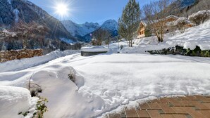 A snow-covered landscape with a clear sky, mountains, and a building with a snow-covered roof. - House Alvier - 3-Room apartment Rothorn with terrace (Brand)
