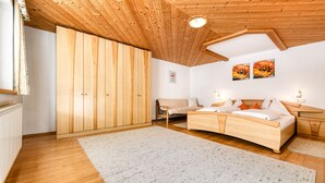 A bedroom with a wooden ceiling, a bed, a nightstand, a chair, and a large wardrobe. - House Alvier - 3-Room apartment Rothorn with terrace (Brand)