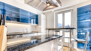 Una cucina moderna con un piano di lavoro in granito, elettrodomestici in acciaio inossidabile e una parete divisoria in vetro.