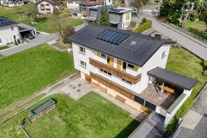 Una casa moderna de dos pisos con un garaje grande, un balcón y un techo con paneles solares.