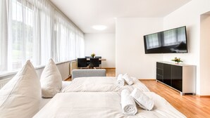 Une chambre d’hôtel moderne avec un grand lit, un bureau et un téléviseur fixé au mur.