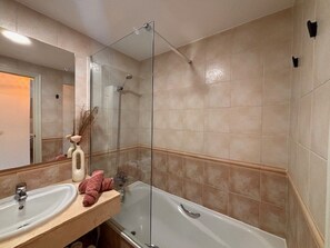 Une salle de bain avec une baignoire, un lavabo, un miroir et un porte-serviettes.