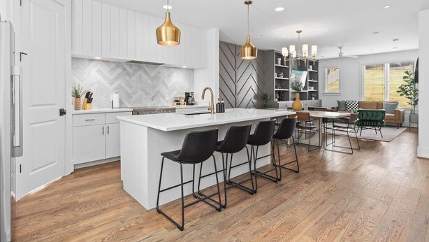 A modern kitchen with white cabinetry, a marble backsplash, and a central island with bar stools. - Stunning Home with Garage, Patio - Walk to Restaurants & Coffee (Nashville)