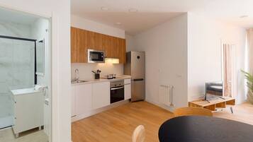 A modern kitchen with white cabinets, a microwave, a refrigerator, and a dining area with a table and chairs.